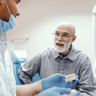 An older male patient talking to a dentist