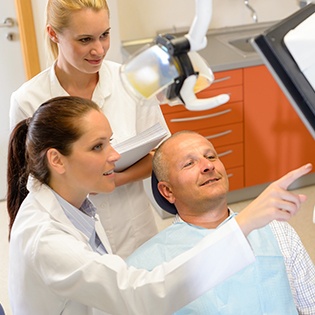 A male patient looking at a screen that is being discussed by his dentist