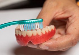 Man brushing his dentures