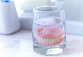 Dentures soaking in a glass