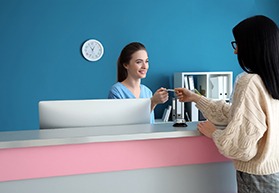 Patient at dental office front desk, paying for treatment