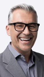 man in suit with glasses smiling
