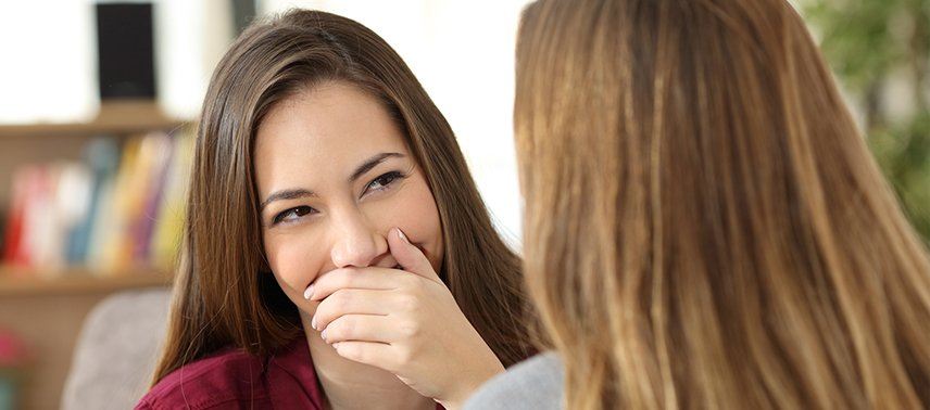 woman covering smile and laughing