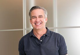 man in grey shirt smiling