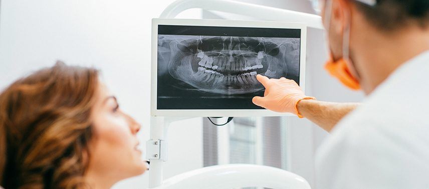 dentist pointing to x-ray on screen