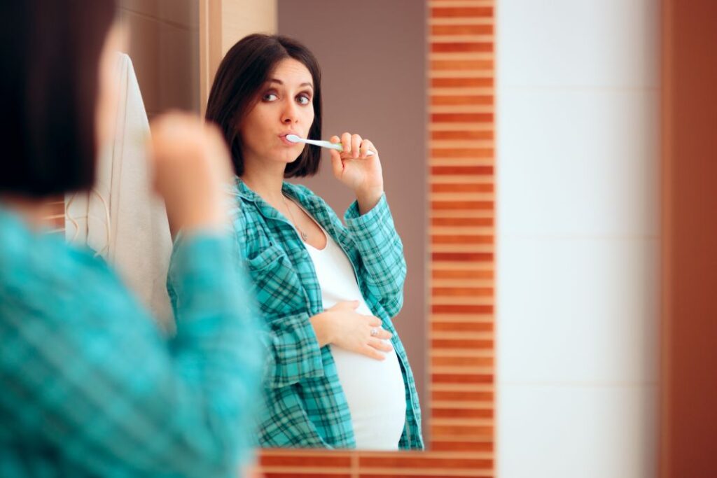A pregnant woman brushing her teeth.
