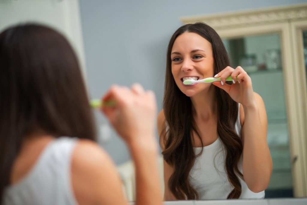 Woman brushing her teeth after eating breakfast.
