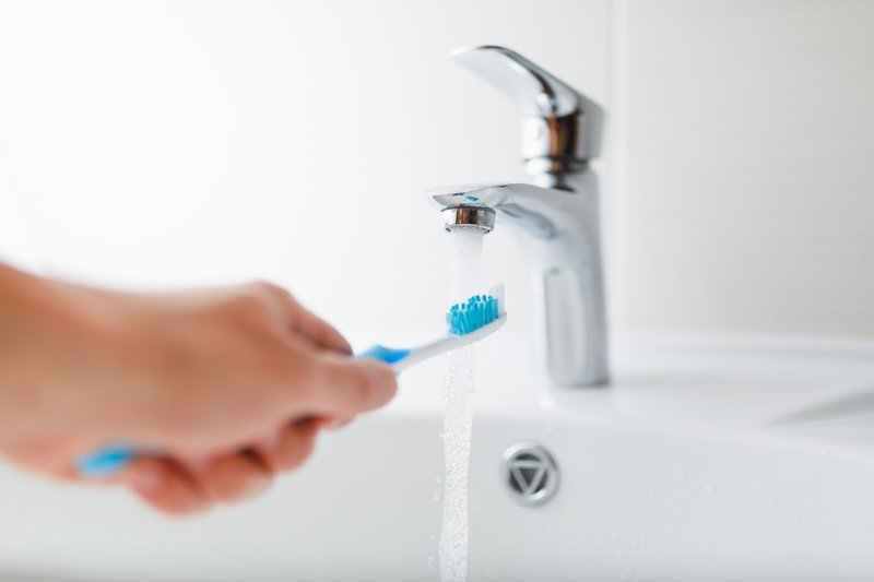 person cleaning their toothbrush