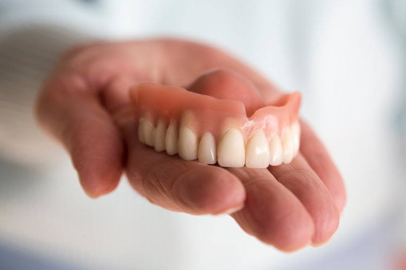 A hand holding ill-fitting dentures